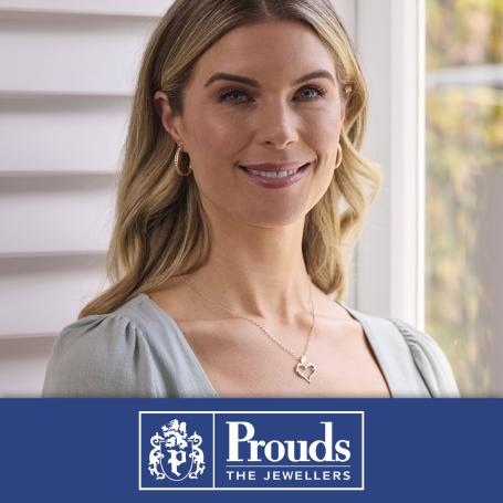 A woman wearing beautiful earrings and necklace. Prouds logo at the bottom, 'Prouds the jewellers'.